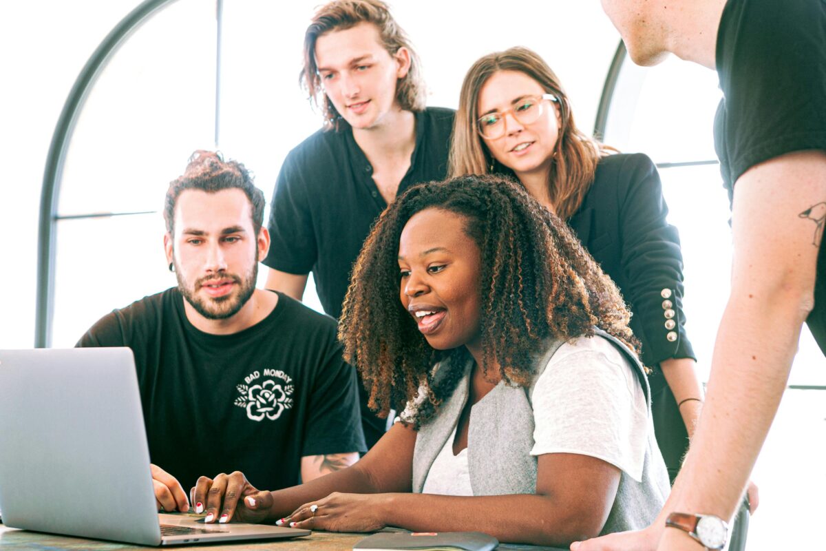A group of people looking at a laptop together