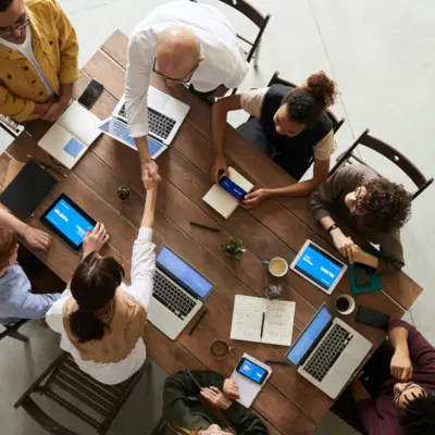 Several people working on computers at a table, two of which are shaking hands