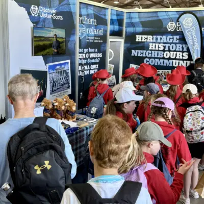 Crowd of people exploring Ulster-Scots heritage and history exhibition booth with informational displays and souvenirs.