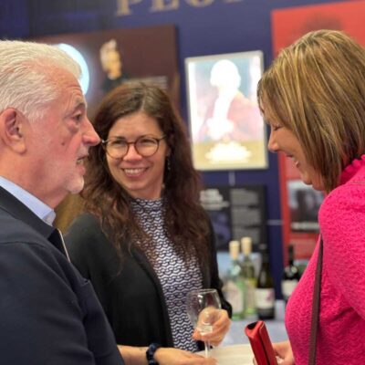 Three adults engaged in a lively conversation at an event inside a museum setting.