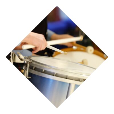 Close-up of a young man's hands as he plays a snare drum with white wooden drumsticks.