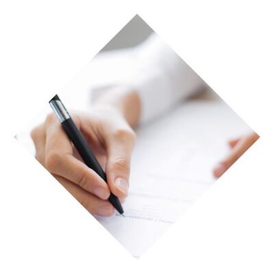 A woman filling out an application form with a black pen on a wooden table next to a white coffee cup.
